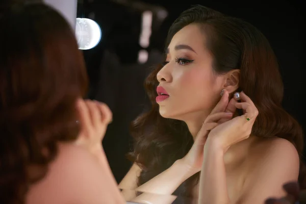 Atractiva Mujer Asiática Mirando Espejo Poniéndose Pendientes Mientras Prepara Para —  Fotos de Stock