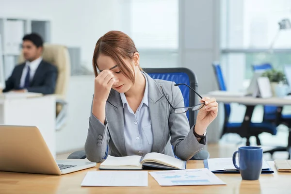 经理坐在职场桌上 疲惫的女人摸着闭着眼睛的鼻子 — 图库照片