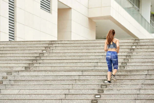 在户外楼梯上奔跑的女人的背部视图 — 图库照片