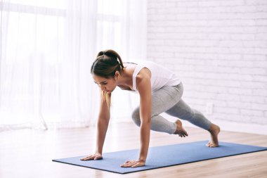 Asyalı kadın egzersiz Yoga Mat evde tuğla duvar ve pencere ile ışık odada yapmak 