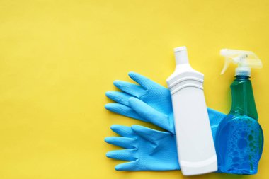 mavi lastik eldiven ve parlak sarı zemin üzerine deterjanlar