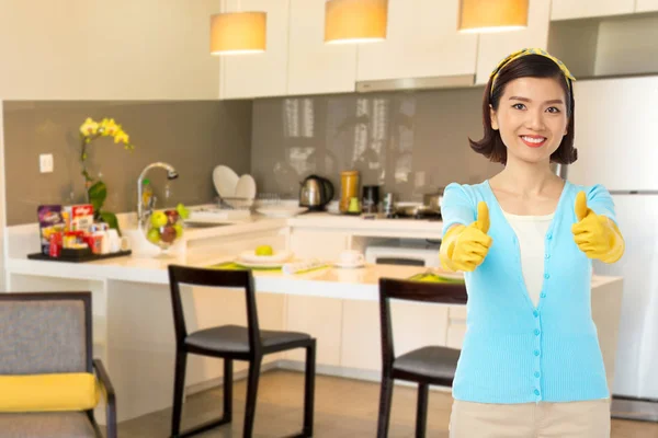 キッチンに立っている間示すゴム手袋で幸せなベトナム主婦親指 — ストック写真