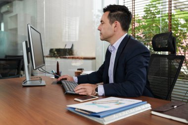 Ofiste bilgisayar ile masada beyaz iş adamı 