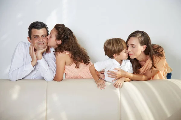 Niños Felices Besando Padres Mejillas Casa Cerca Del Sofá — Foto de Stock