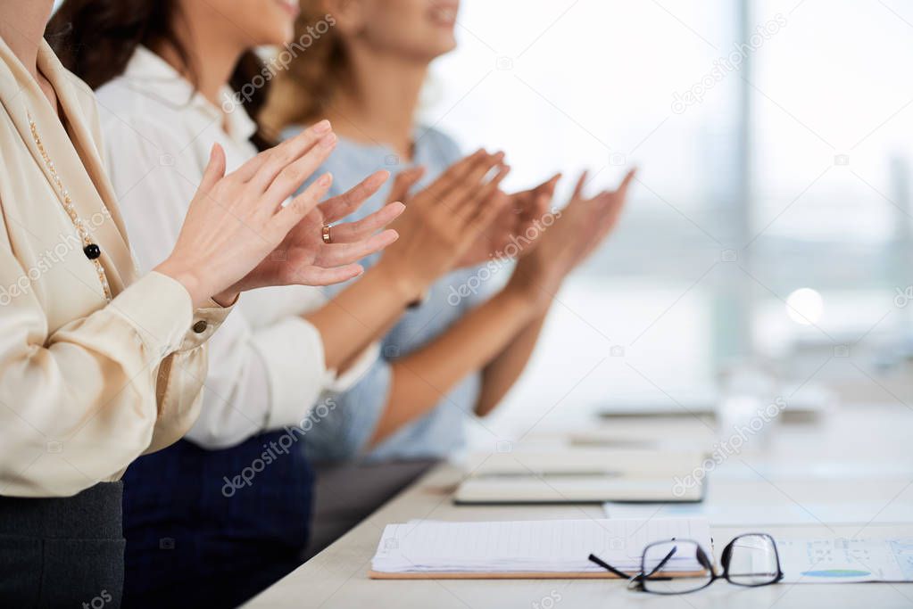 Business women clapping to speaker at conference