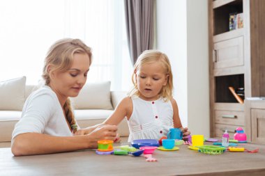 Anne ve kızı renkli plastik çay seti ile oynamak