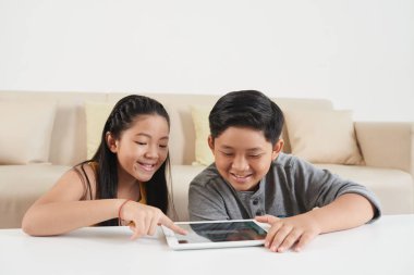 iki Asyalı çocuk, kardeşi ve kız kardeşi dijital tablet masada kullanma