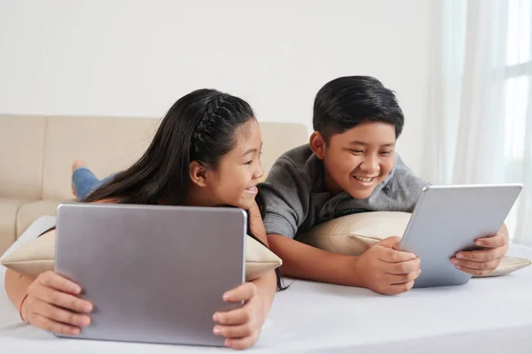 Iki Asyalı Çocuklar Dizüstü Bilgisayar Dijital Tablet Yatakta Yatarken — Stok fotoğraf