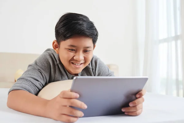Αγόρι Χαμόγελο Περιήγηση Ψηφιακή Δισκίο Στο Κρεβάτι Στην Κρεβατοκάμαρα — Φωτογραφία Αρχείου