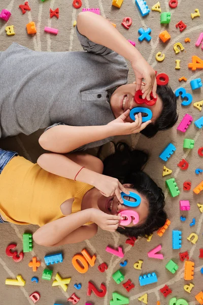Двоє Азіатських Дітей Лежать Підлозі Покривають Очі Барвистими Пластиковими Номерами — стокове фото