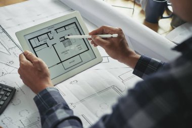 Planı elinde mimar bina ile tablet bilgisayar