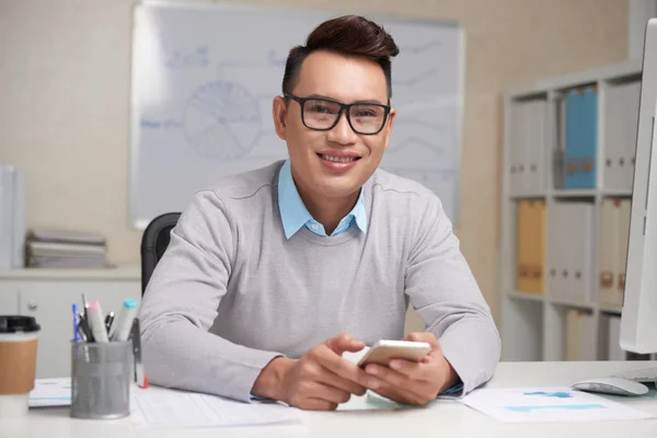 Alegre Hombre Negocios Vietnamita Gafas Con Teléfono Inteligente Sentado Mesa —  Fotos de Stock