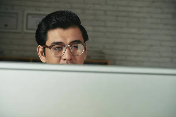 戴眼镜的亚洲人在电脑屏幕上阅读信息 — 图库照片