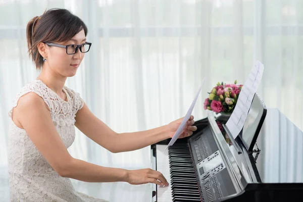 年轻的亚洲女性在钢琴伴奏下学习新旋律 — 图库照片