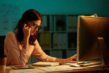 Dalgın iş kadını kağıtları ve bilgisayar ile masada planlayıcısındaki zamanlama denetimi