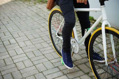 Tanınmayan adam binicilik bisiklet güneş ışınları ile aydınlatılmış şehrin cadde boyunca