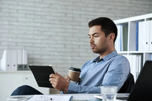 Seriöser Geschäftsmann Trinkt Kaffee Und Liest Informationen Auf Tablet Computer — Stockfoto