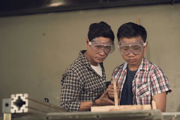 asian son and father carpenters working with wood in workshop, saw wood