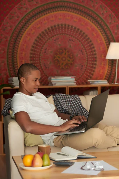 Jovem Negro Sentado Sofá Casa Trabalhando Laptop — Fotografia de Stock