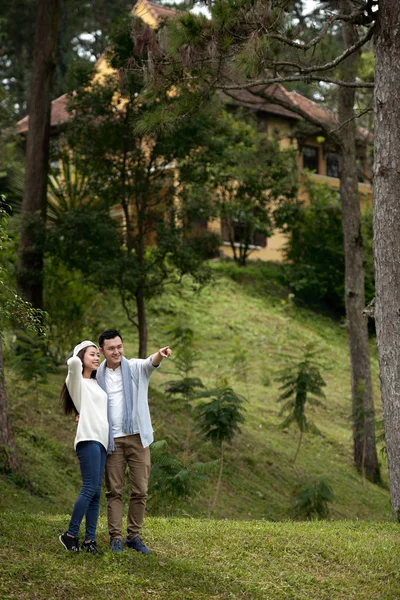 快乐的年轻亚洲夫妇在绿色森林 男子指着手指 — 图库照片