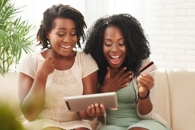 Heyecanlı Afrikalı-Amerikalı kadın büyük online mağaza içinde dijital tablet tarama bulundu 