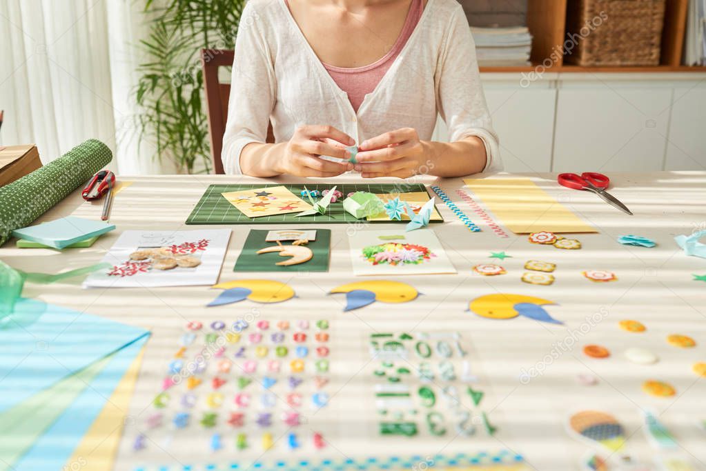 designer woman sitting at wooden table and making herbarium decor art picture 