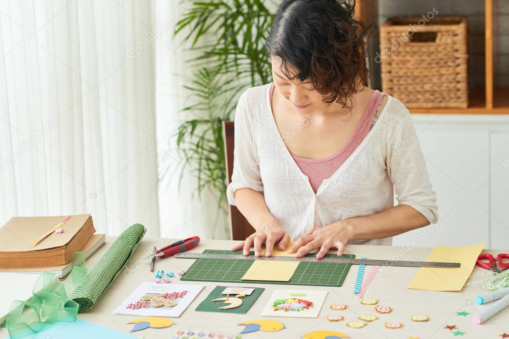 Creative woman sitting at wooden table and making herbarium decor art picture 