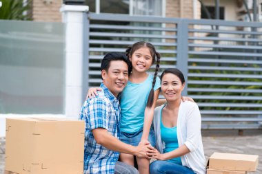 Evin önünde üç duran mutlu bir aile portresi