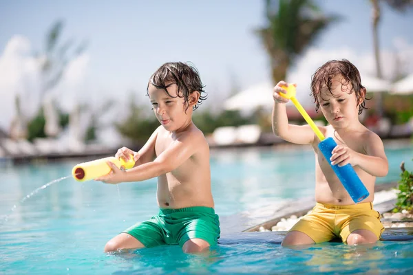 Children playing with water guns in swimming pool