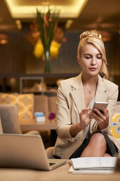 Blonde Geschäftsfrau Liest Nachricht Smartphone Während Sie Auf Sofa Hotellobby — Stockfoto