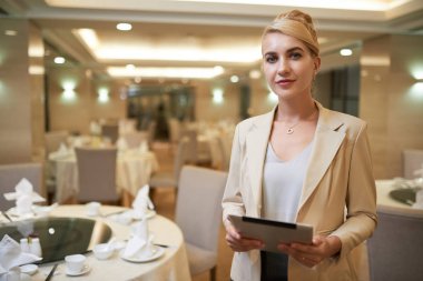 Kamera için poz ve klasör tutan otel restoranında çok gülümseyen sarışın kadın Yöneticisi 