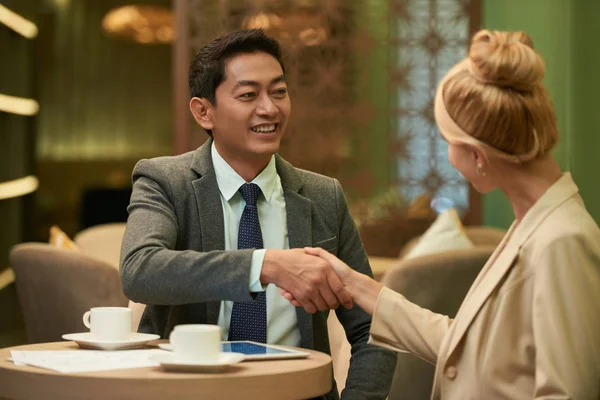 Веселый Вьетнамский Бизнесмен Пожимает Руку Блондинке Столом Кафе — стоковое фото