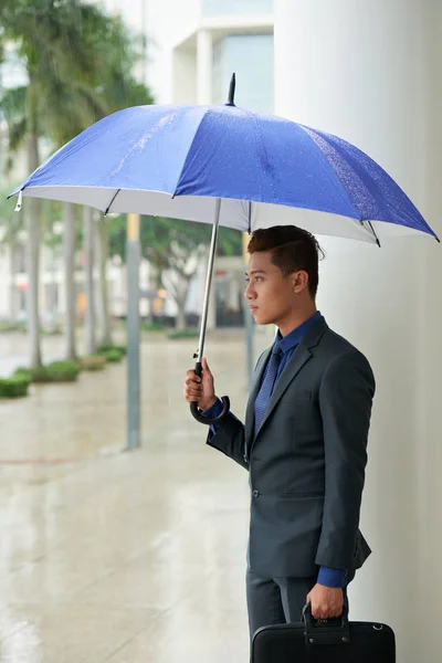 忧郁的亚洲商人带着蓝色雨伞户外雨天天气 — 图库照片