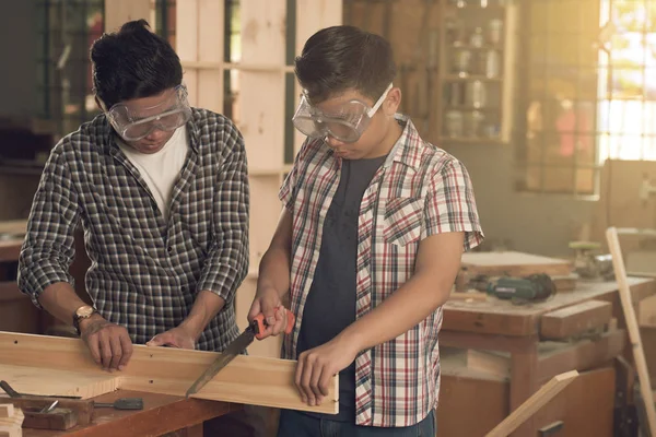 carpenters father and son sawing wooden plank