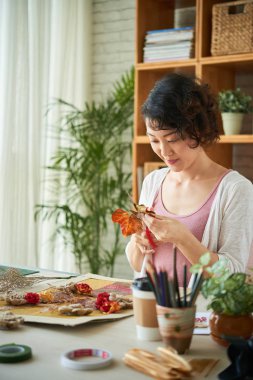 Kolaj yapmak için genç Vietnamlı kadın kesme kuru çiçek gülümseyen