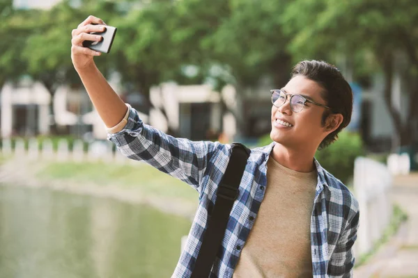 愉快的亚洲人戴着眼镜自拍现代智能手机 同时享受在公共公园愉快的散步 — 图库照片