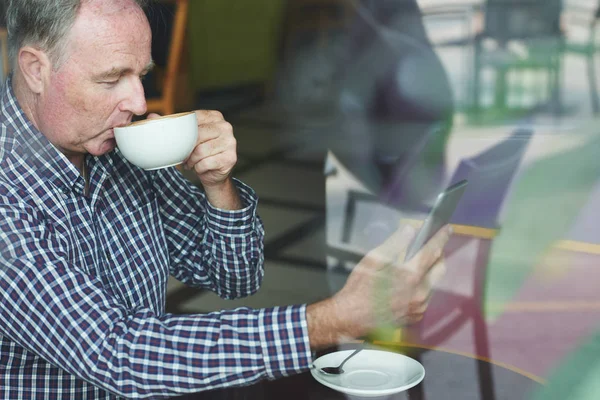 Starszy Mężczyzna Ciesząc Się Filiżankę Cappuccino Przeglądanie Cyfrowych Tabletu Kawiarni — Zdjęcie stockowe