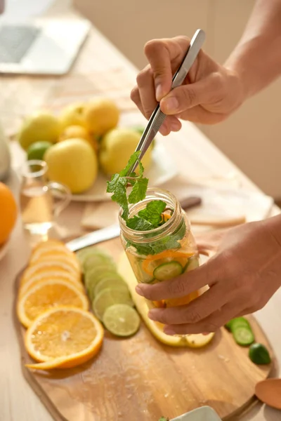 Mulher Aplicando Ingredientes Para Água Infundida Cítrica Recipiente Com Pinças — Fotografia de Stock