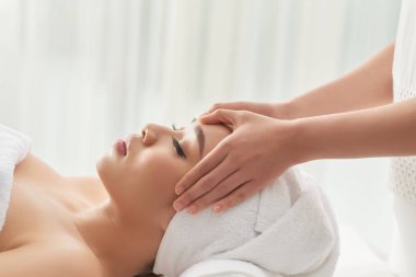 Kırpma ellerin dikkatle güzel Bayan alnına spa oturum sırasında salonda sürtünme terapist masaj