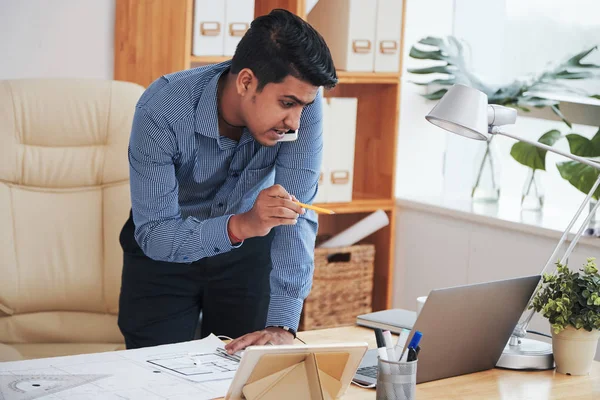 印度成年商人用铅笔指着笔记本电脑 与智能手机通信 — 图库照片