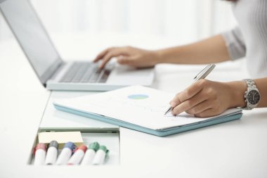 Dizüstü bilgisayar ve ofis masası çalışma kağıt üzerinde yazma modern kadının yüzü olmayan atış