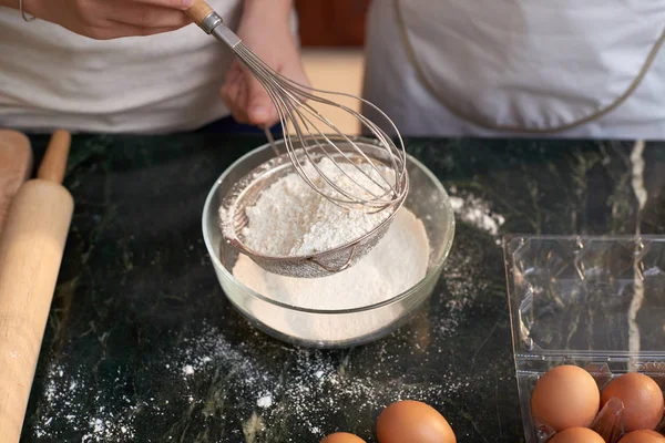 近距离观察无法辨认的妇女拿着面粉的筛子 并准备在做饼干面团时用鸡蛋搅拌 — 图库照片