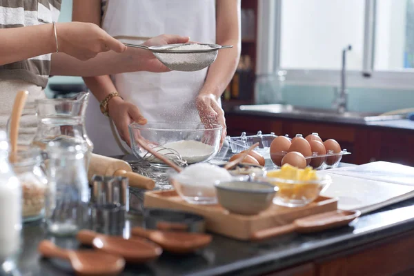 无法辨认的妇女在厨房柜台前用产品和炊具筛选面粉以换取饼干面团 — 图库照片