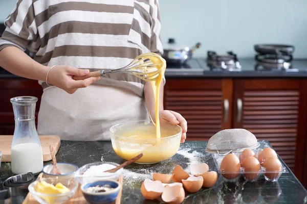 无法辨认的女性站在凌乱的厨房桌旁 用面粉和糖搅拌鸡蛋的作物镜头 — 图库照片