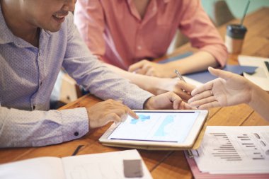 Grup tablet ile masada toplama ve takım grafikte tartışırken iş adamları