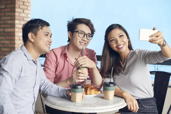 快乐的现代亚洲同事与咖啡和面包在咖啡店采取自拍与电话 — 图库照片