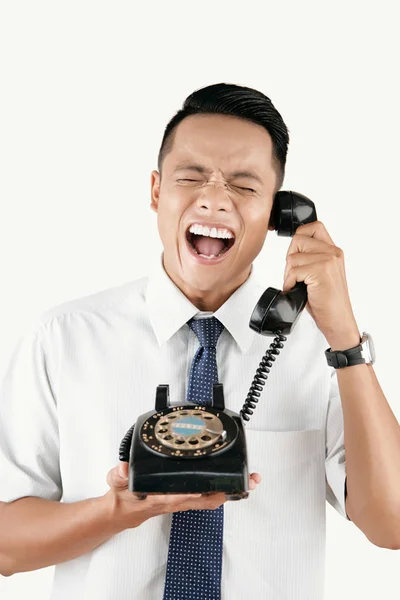 アジア青年ビンテージ ロータリー ダイヤル電話で誰かに話していると白い背景に対する彼の怒りを表現します — ストック写真