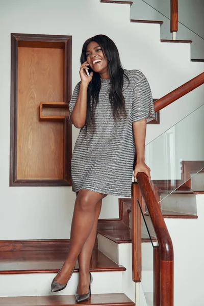 时尚成年黑人妇女穿着礼服站在现代房子的楼梯上有电话 — 图库照片