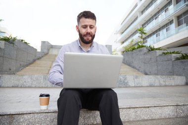Basamaklarında oturan ve dizüstü bilgisayarda çalışma neşeli iş yürütme