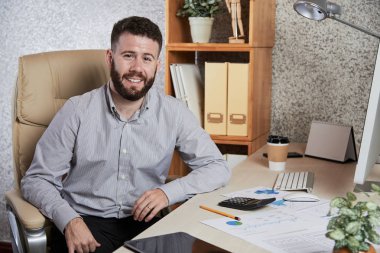 Neşeli genç yakışıklı iş yürütme masasında belgeleriyle çalışma